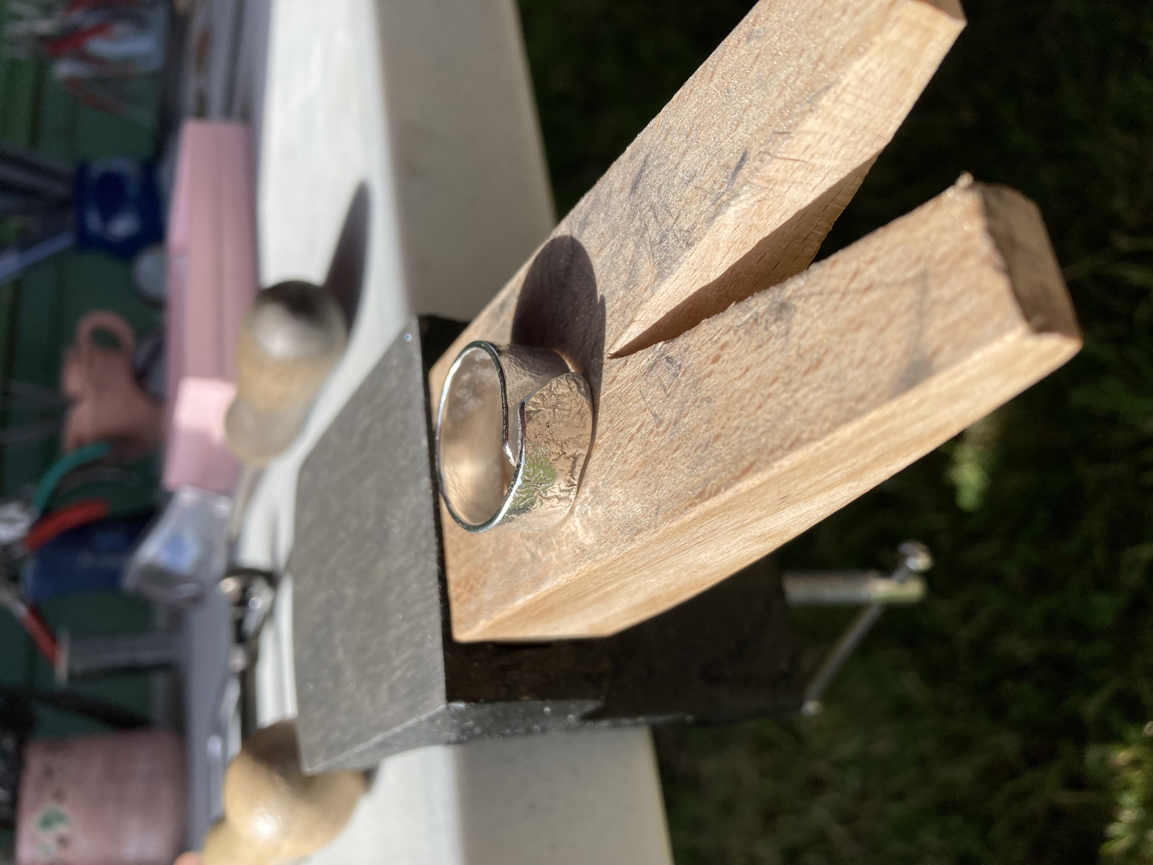 Sterling silver ring resting on a wooden block at the outdoor workshop