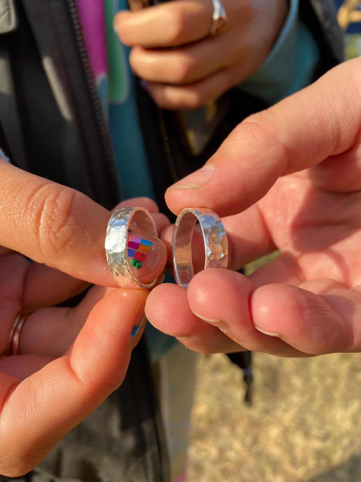 Two freshly made hammered sterling silver rings held up by their makers